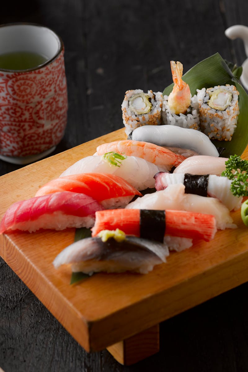 Elegant display of sushi with green tea on a wooden board, capturing authentic Japanese cuisine.